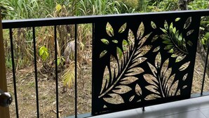 A balcony with a metal railing, overlooking a lush garden with various plants and trees. - Las Casitas italiana (Sabalito)
