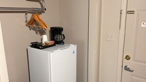 Una kitchenette compacta con un refrigerador blanco, una cafetera y un microondas.