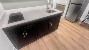 A modern kitchen with a double sink, black cabinets, and a stainless steel refrigerator. - Value Suites Extended Stay (Sacramento)
