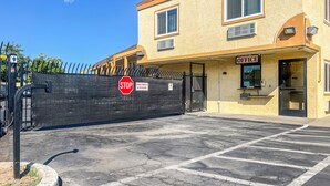 A two-story building with a 'STOP' sign, a gated entrance, and an 'OFFICE' sign. - Value Suites Extended Stay (Sacramento)
