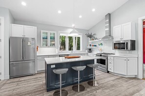 A modern kitchen with a central island, stainless steel appliances, and bar stools.