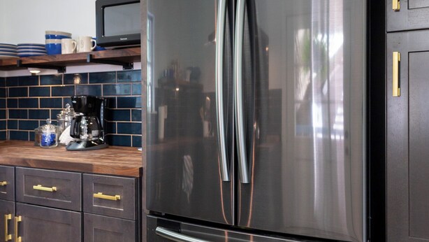 A modern kitchen with dark cabinetry, a stainless steel refrigerator, and a patterned tile floor.