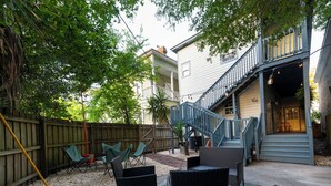 A backyard with outdoor seating, a wooden fence, and a staircase leading to a porch.