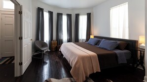 A bedroom with a bed, a chair, a bedside table, and a ceiling fan.