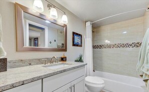 A bathroom with a sink, mirror, and shower.