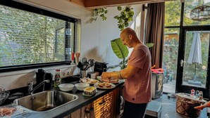 A modern kitchen with a large window, wooden cabinets, and a countertop with food items.