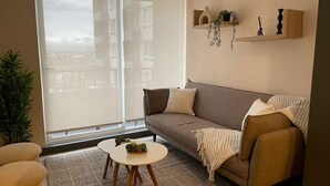 Ein modernes Wohnzimmer mit einer Couch, einem kleinen runden Tisch und einem großen Fenster.