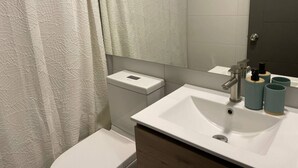 Ein modernes Badezimmer mit Waschbecken, Spiegel und Toilette in Weiß.