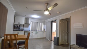 A compact kitchen with white cabinets, a microwave, and a ceiling fan.