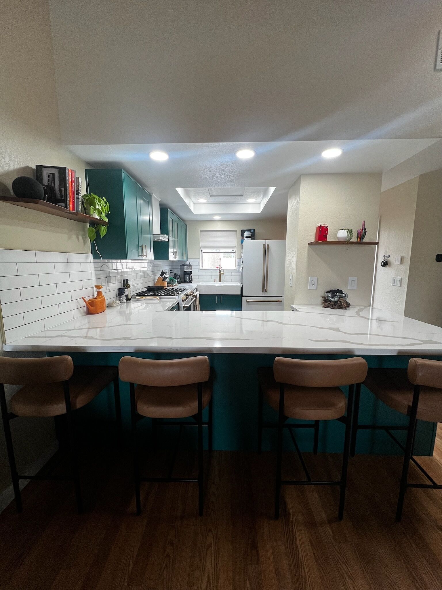 Una cocina moderna con una isla central, taburetes de bar y un horno empotrado.