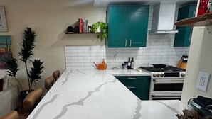 A kitchen with white marble countertops, teal cabinets, and a built-in oven. - Stylish Ocean Beach Townhouse - Walk to the Sand, Relax in Comfort (San Diego)