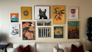 A living room with a sofa and various framed artworks on the wall. - Stylish Ocean Beach Townhouse - Walk to the Sand, Relax in Comfort (San Diego)