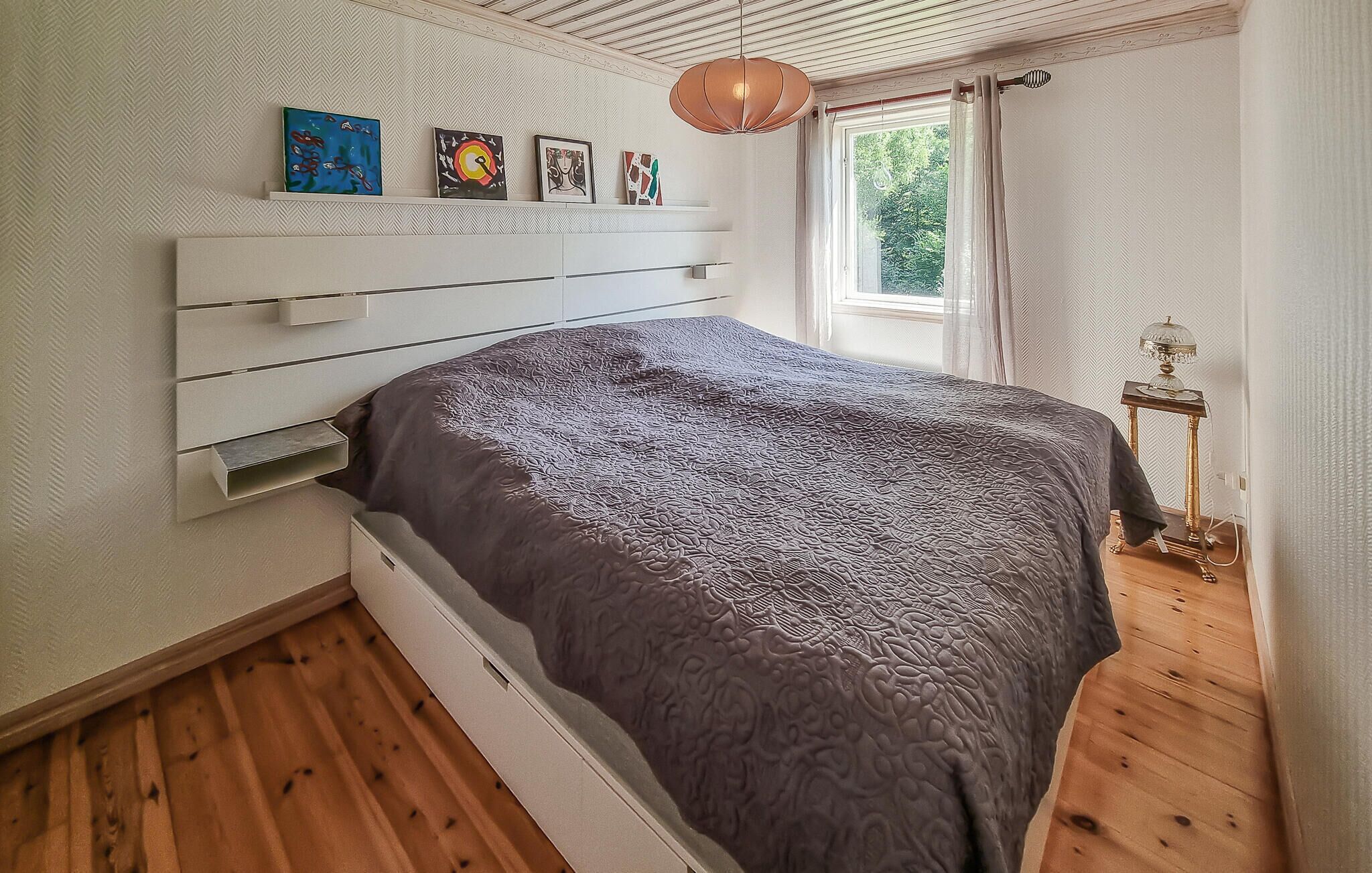 Ein Schlafzimmer mit Bett, Fenster und Nachttisch.
