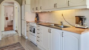 A kitchen with white cabinets, a double oven, a sink, and a coffee maker. - Awesome home in Värnamo with lake view (Värnamo)