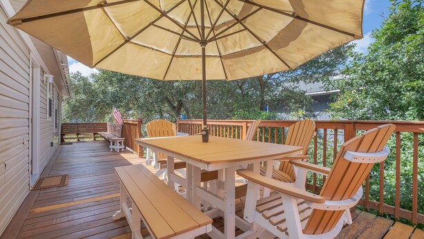 A wooden deck with a table and chairs under a large umbrella. - 5485-Hammerhead Harbour, Old Nags Head Cove | Pet-Friendly Coastal Escape (Nags Head)
