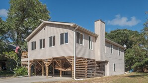 A two-story house with a covered porch and a chimney. - 5485-Hammerhead Harbour, Old Nags Head Cove | Pet-Friendly Coastal Escape (Nags Head)