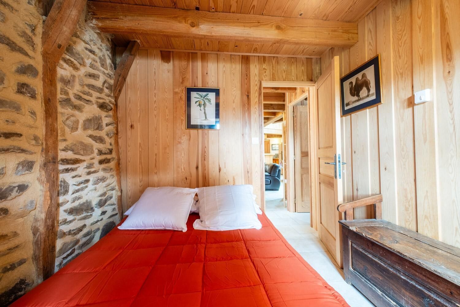 A narrow room with a bed, wooden walls, and a stone wall.