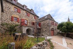 Ein Gebäude aus Stein mit roten Fensterläden, einer Treppe und einem kleinen Garten.