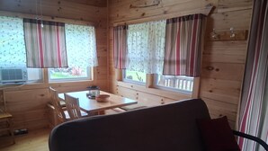 A wooden cabin interior with a sofa, a dining table, and two windows with curtains. - Private cabin on the beautiful Kickapoo River Valley near Wildcat Mountain Park. (Ontario)