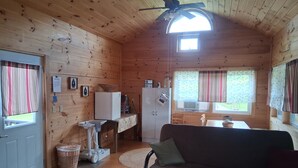 A wooden cabin interior with a kitchenette, a sofa, a ceiling fan, and a window with curtains. - Private cabin on the beautiful Kickapoo River Valley near Wildcat Mountain Park. (Ontario)