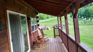 A wooden deck with a glass door, a rocking chair, and a table with chairs. - Private cabin on the beautiful Kickapoo River Valley near Wildcat Mountain Park. (Ontario)