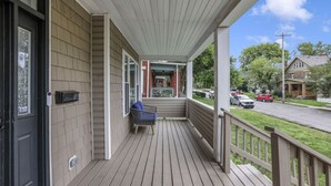 A covered porch with a wooden deck, a black door, and a mailbox. - The Vibe at OSU: Walking distance to the stadium! (Columbus)