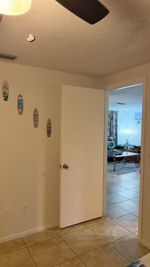 Quarto com porta branca, piso de azulejos e ventilador de teto.