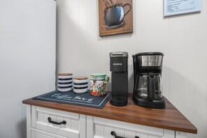 A kitchen counter with a coffee maker, a Keurig, and a glass carafe. There are striped and floral containers on the counter. - Hailey's Retreat- 3/2 Cozy & Spacious Home + Sunroom- 6 min to Downtown Dothan! (Dothan)