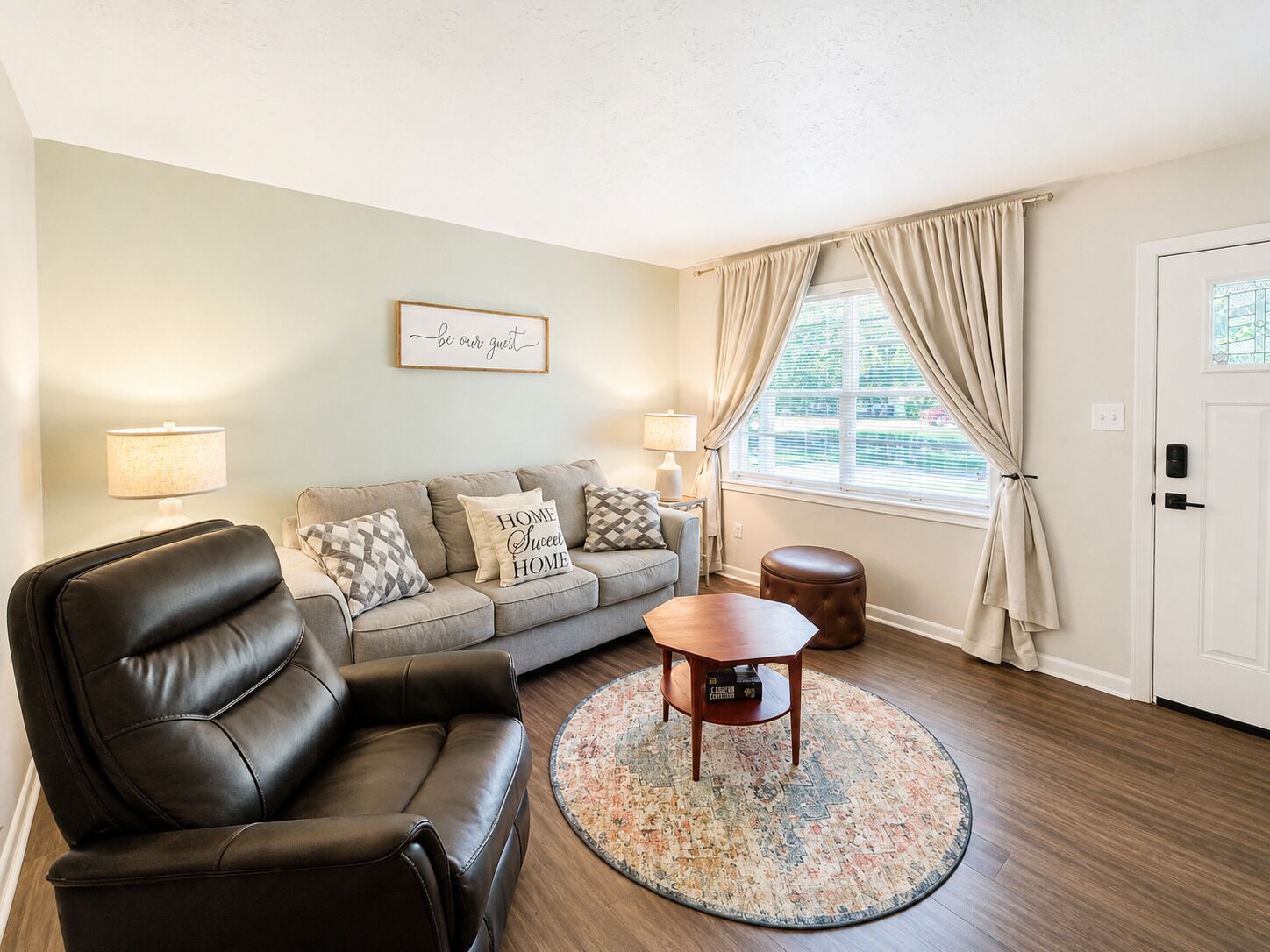 A living room with a leather sofa, a wooden coffee table, and a patterned rug.
