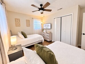 A hotel room with two beds, a ceiling fan, a desk with a lamp, a dresser, and a framed picture on the wall. - Hailey's Retreat- 3/2 Cozy & Spacious Home + Sunroom- 6 min to Downtown Dothan! (Dothan)