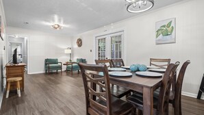 A dining area with a wooden table, chairs, and a chandelier.