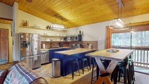 Una cocina moderna con una isla central, electrodomésticos de acero inoxidable y techo de madera.