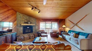 Una sala de estar acogedora con chimenea de piedra, sofás de cuero y una televisión.