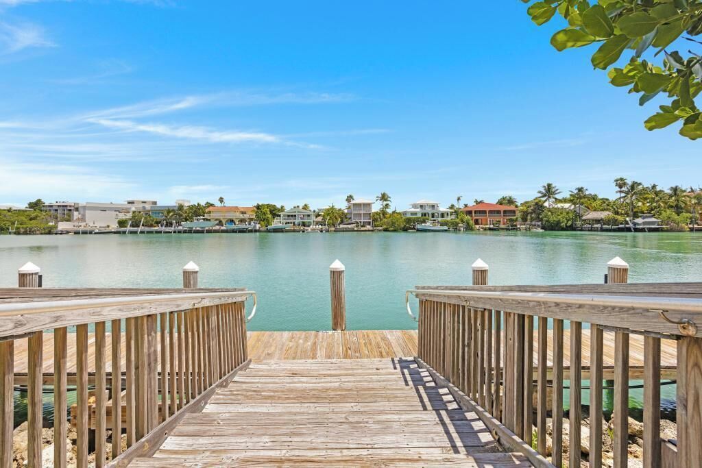 A wooden pier leading to a calm body of water with buildings in the background.