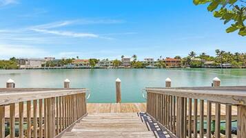 A wooden pier leading to a calm body of water with buildings in the background.