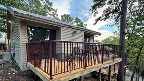 A small cabin with a wooden deck and a metal railing, surrounded by trees. - Rustic Table Rock Cabin - Minutes to the Lake! (Kimberling City)