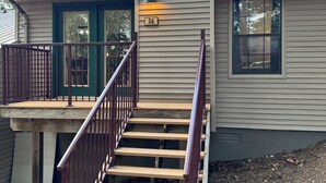 A residential house with a wooden staircase, a porch with a railing, and a mailbox. - Rustic Table Rock Cabin - Minutes to the Lake! (Kimberling City)