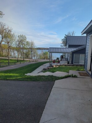 A residential property with a covered patio, a lawn, and a view of a lake.