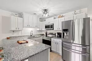 A modern kitchen with white cabinets, stainless steel appliances, and a granite countertop. - Quiet Coastal Getaway King Bed • Pools • Private Balcony • Near Beach • Sleep 6 (Little River)