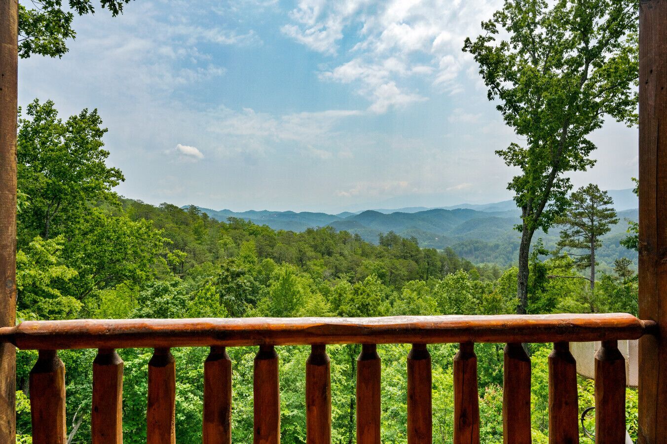 Un balcon en bois offrant une vue sur une chaîne de montagnes boisées.