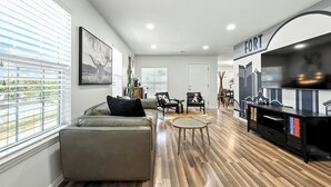 A modern living room with a sofa, chairs, a coffee table, and a TV stand. - Boots & Bedrolls - Walkable to Fort Worth's Dickies Arena. (Fort Worth)