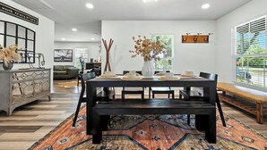 A modern dining area with a dark wooden table, black chairs, and a bench. There is a decorative vase with dried flowers on the table. - Boots & Bedrolls - Walkable to Fort Worth's Dickies Arena. (Fort Worth)