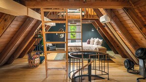 A loft bedroom with a wooden ceiling, a bunk bed, a spiral staircase, and a small desk area. - Packwood: Chalet + Nest (Packwood)