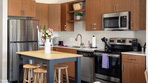 A modern kitchen with wooden cabinets, stainless steel appliances, and a central island with stools.