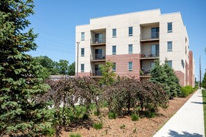 Un immeuble résidentiel à plusieurs étages, doté de balcons et entouré d’espaces verts aménagés.