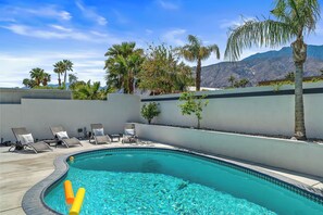 Une piscine avec des chaises longues et des palmiers.