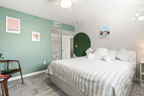 Une chambre à coucher avec un lit, une chaise, une porte et un mur décoré de tableaux.