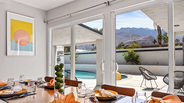 A dining area with a view of a pool and mountains.