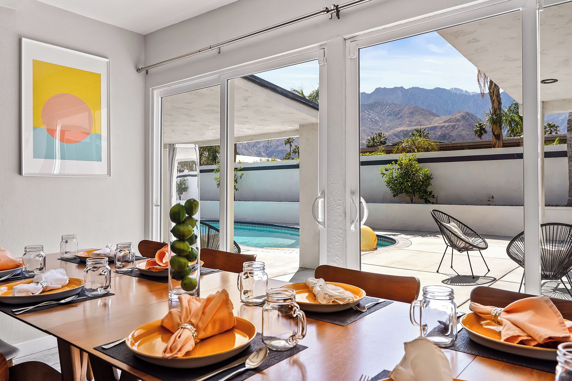 A dining area with a view of a pool and mountains.