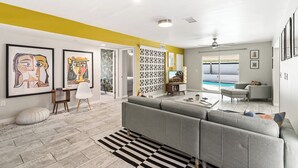 A modern living room with a grey sofa, a striped rug, and a pool view through the sliding doors.